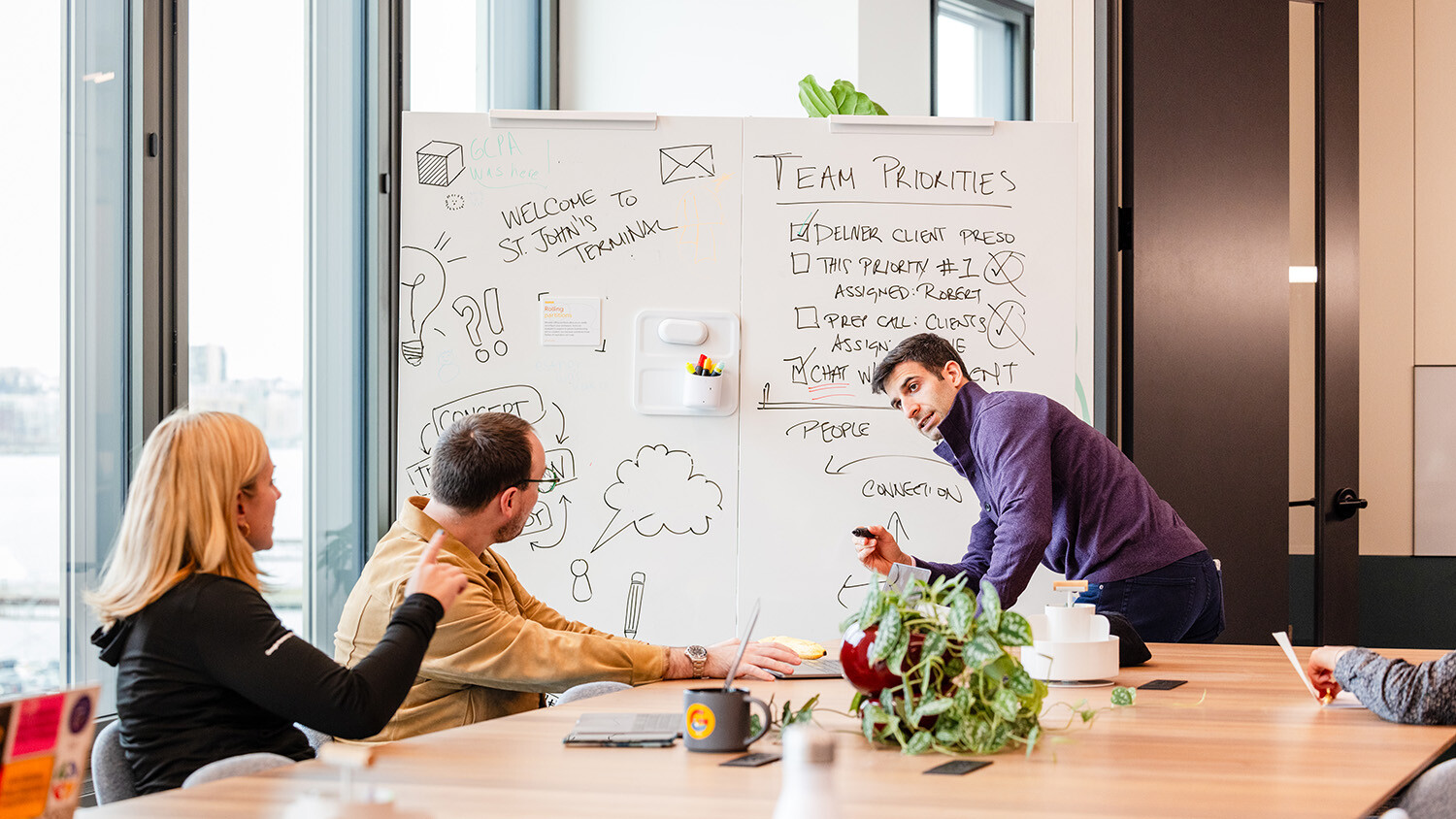 Employee writing on whiteboard during meeting with colleagues